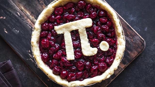 A top-down view of a cherry pie on a dark wooden surface, with a golden crust and the mathematical pi symbol plus a dot cut from pastry and placed on top of the glossy red cherry filling. Image from Hugo Aitken on Unsplash