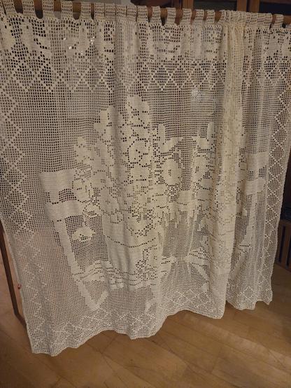 Filet crochet windiw curtain - an overflowing pot of flowers on a deck chair with a row of birds across the top. This is the left side of the curtain. The right side is a mirror image.