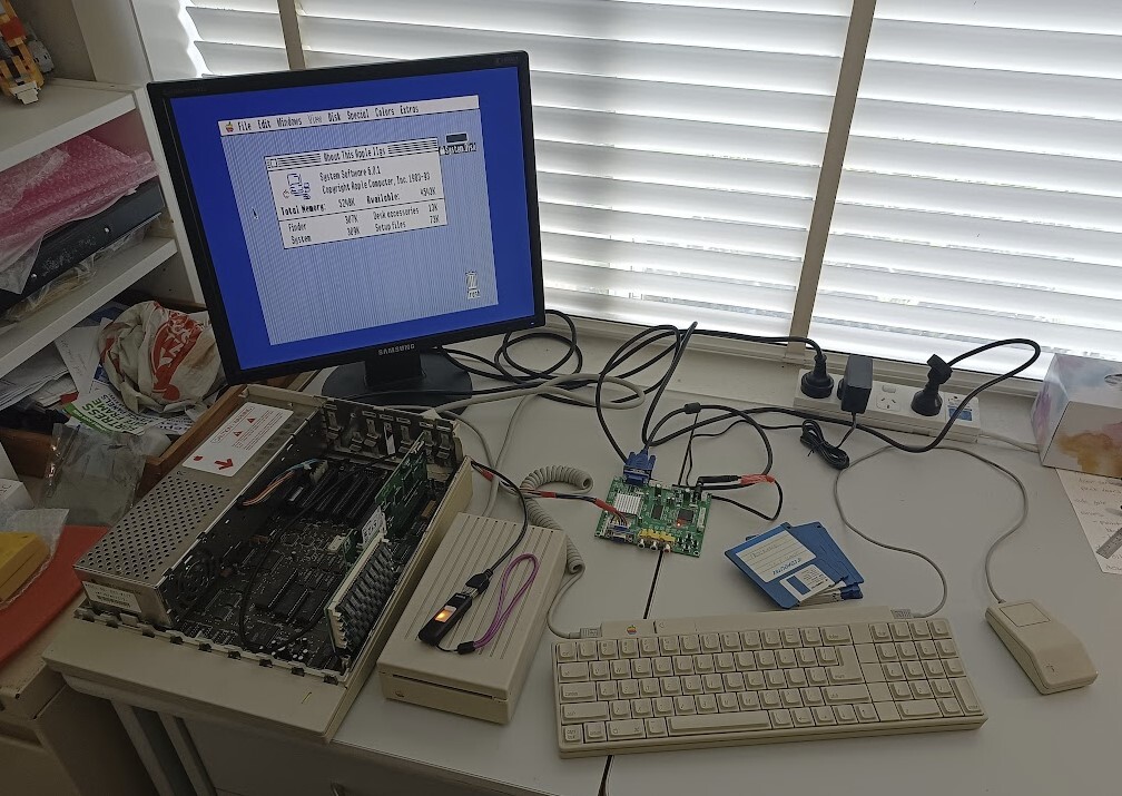 Desk with an open Apple IIGS (with 4MB RAM and CFFA3000 cards), 3.5" drive, keyboard, mouse, GBS82000 video upscaler, Samsung monitor and some floppy disks