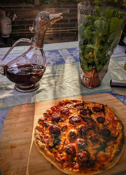 A chorizo pizza, a punnet of basil and a carafe of red wine.