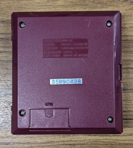 The back cover of the gaming unit showing its manufacturing number and year (MW-56 1983), its intact original battery cover and its serial number of 35890438
