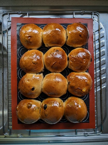 A grid of 12 jam-glazed fruit and spice buns rest on a cooling rack. They're essentially hot cross buns, but without the flour paste cross (which is a minor faff and it's purely cosmetic).
