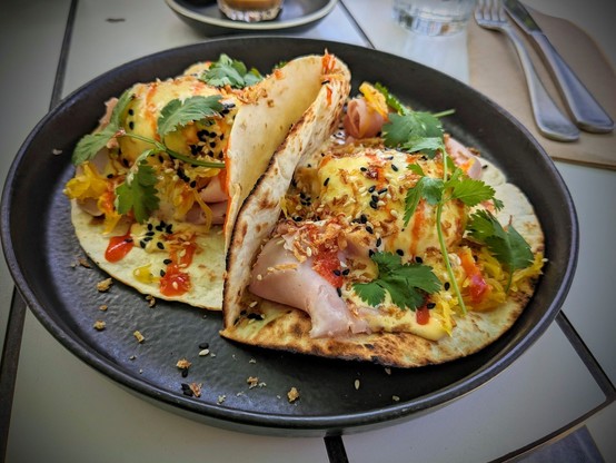 The DS Burrito - 2 toasted tortillas with ham, poached eggs, hollandaise, sriracha, fried shallots, seasame seeds and sprigs of coriander.