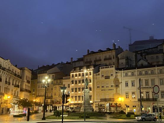 Historic buildings around a plaza lit by streetlights under a dark blue sky 