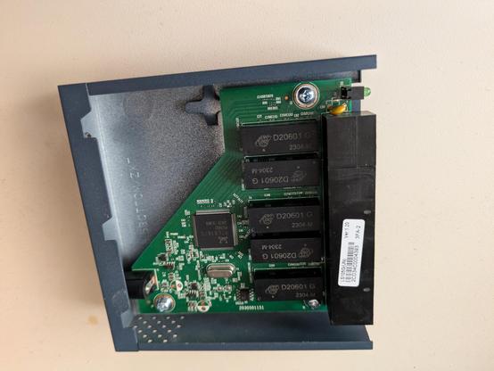 A visible light photograph of the switch with its power jack and power supply circuitry in the lower left corner of a roughly triangular green circuit board.