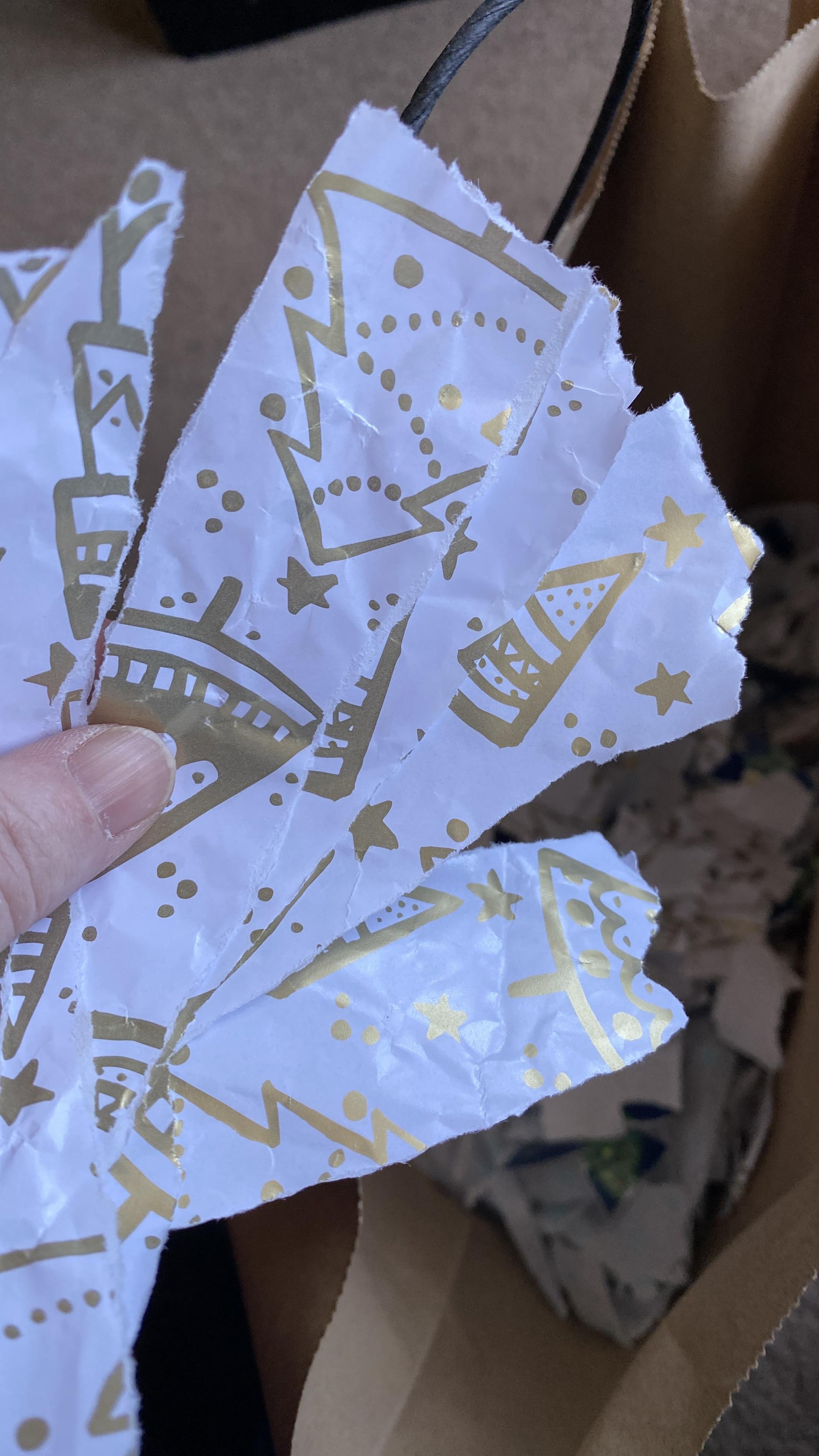 Shreds of white wrapping paper printed with gold Christmas trees.