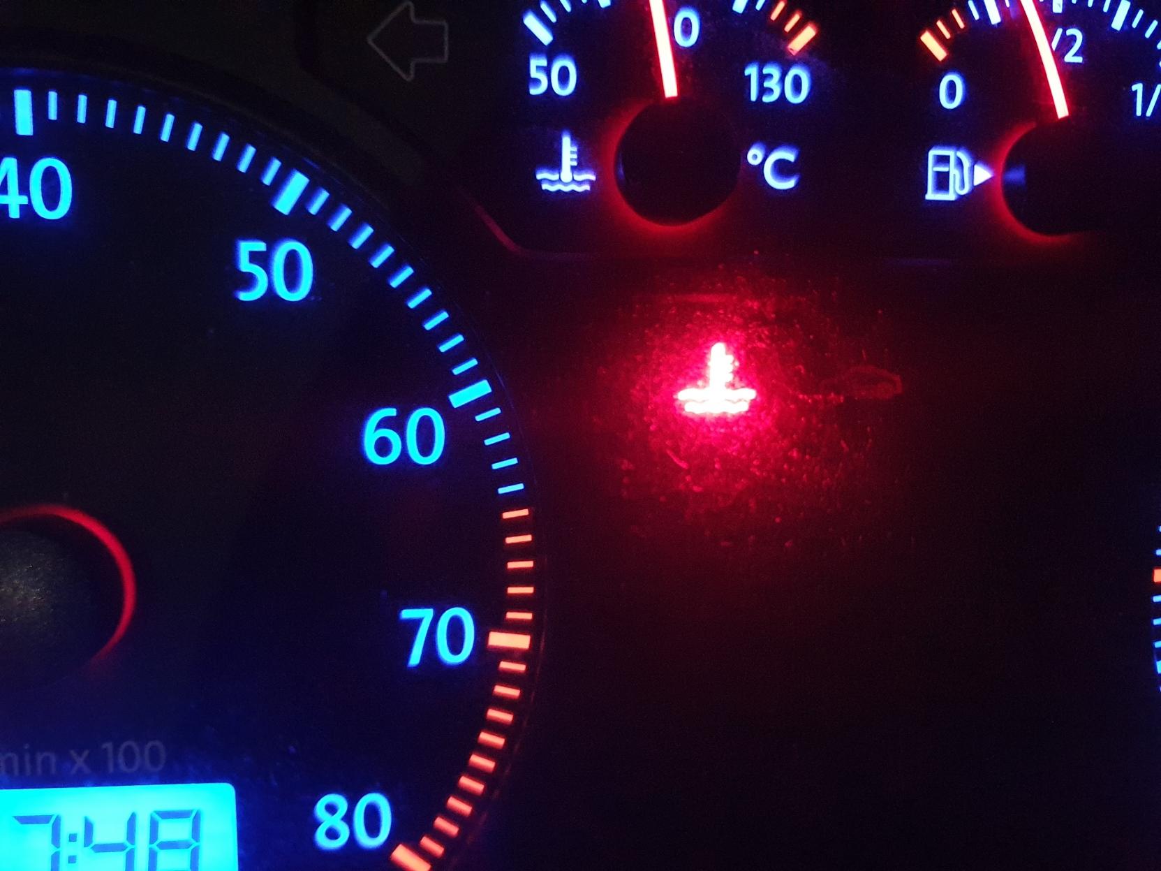 Dashboard lights with a lit up red thermometer light in the middle.