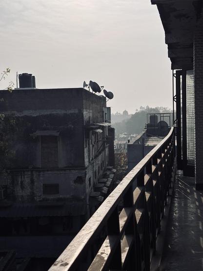 View towards smog-obscured skyline from a balcony surrounded by grey buildings