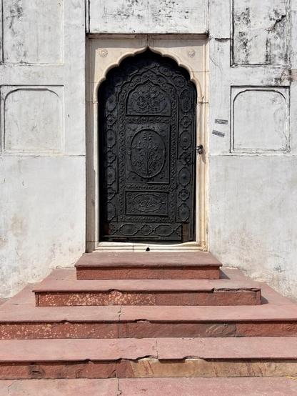 Black doorway in white wall with red sandstone steps 