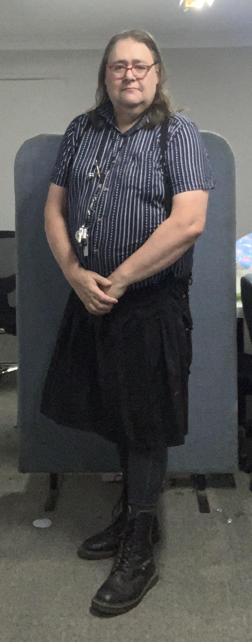 Kit is wearing a men’s shirt, kilt, tights and Dr Martens.