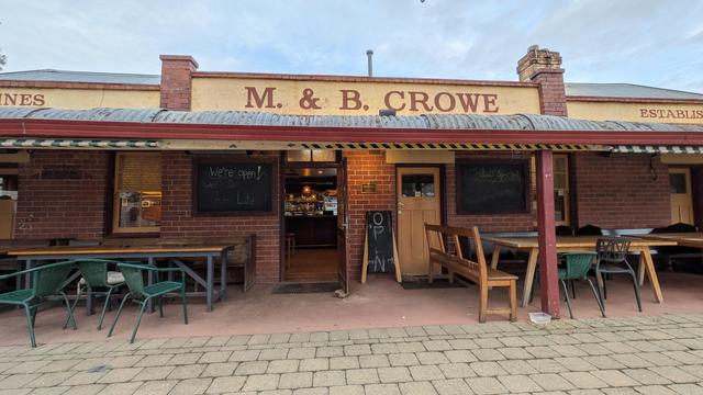The old Star Wine Saloon , with its facade reading "M & B Crowe" over a galvanized iron verandah and outdoor tables.