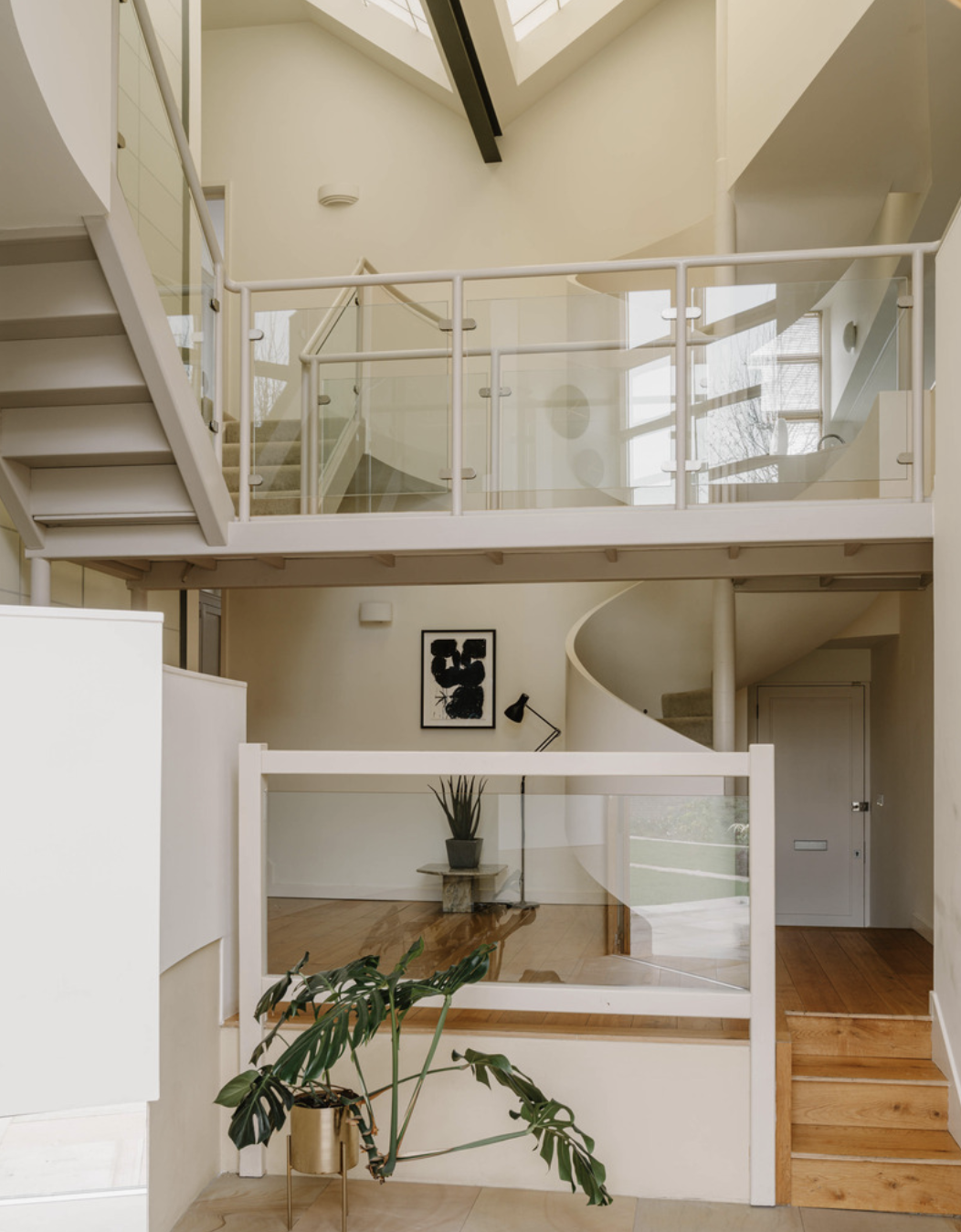 The foyer which shows 3 steps to get up to one part, a spiral staircase off to the right, and on the left you can see 2 lots of stairs going up in different directions from the landing.