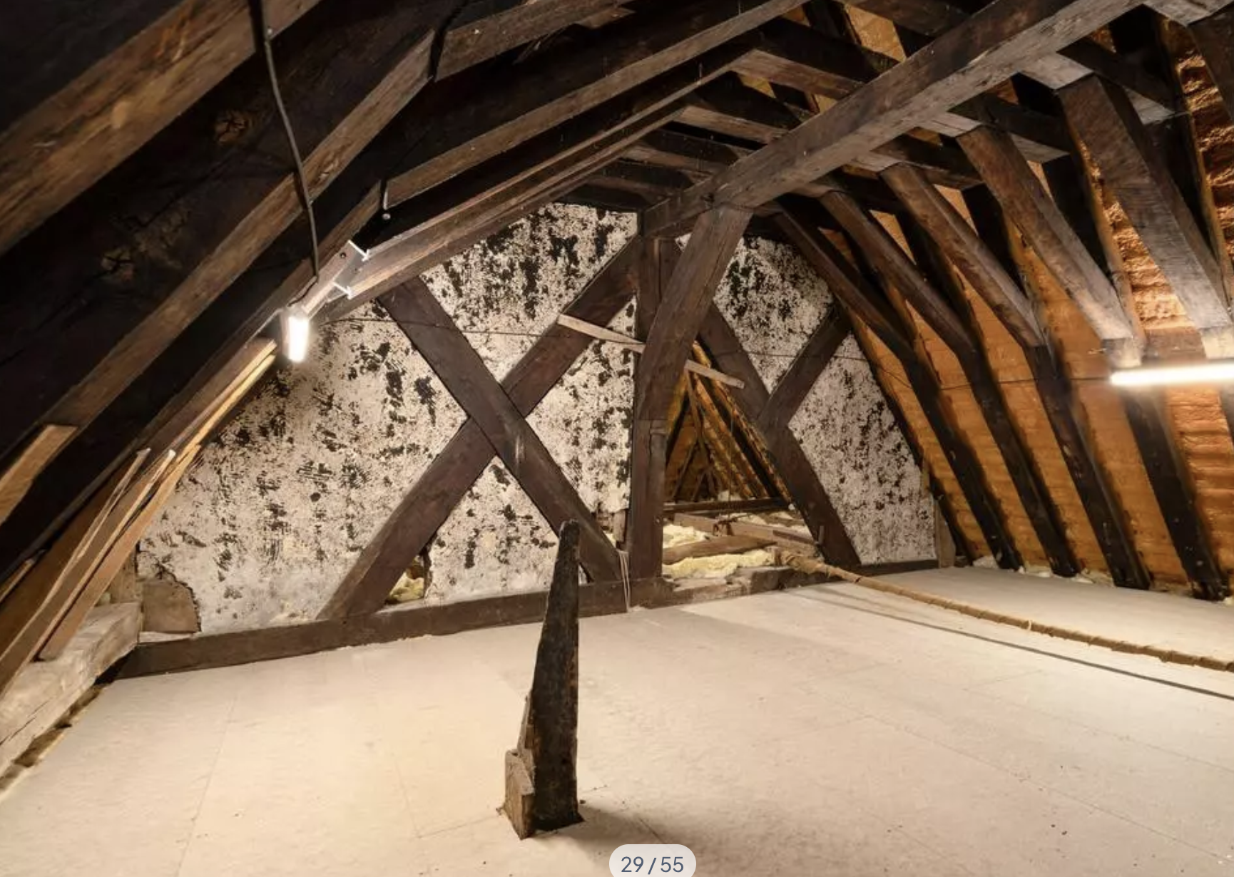 An attic room with wood beams - in the middle of the room a spike of wood pokes up through the floor, and off to the side you can see a rope running across the floow