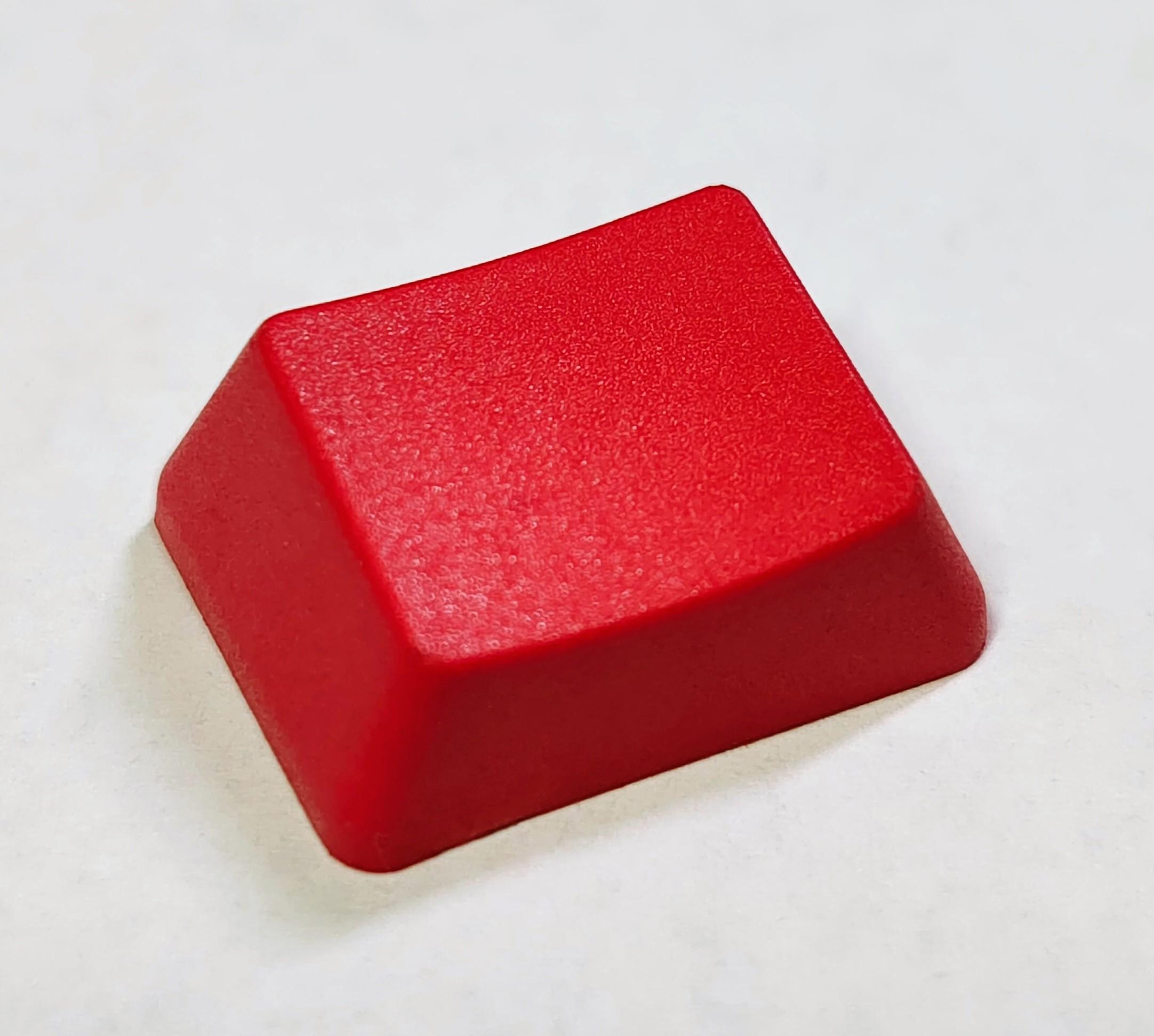 A red OEM profile 1.25u wide keycap on white paper.