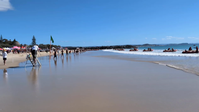 The starting hooter blows and the competitors rush down the beach towards their boats in the water.