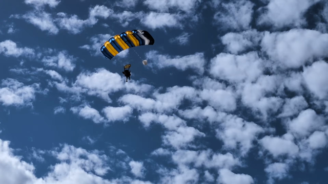 A pair of tandem skydivers loop around and come to a quick and easy stop on the sand.