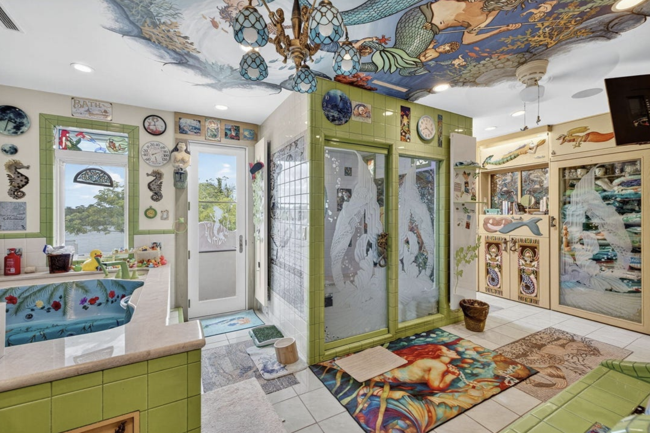 A bathroom with different patterns and different rugs on the floor, including a large bathtub painted with a tropical design inside
