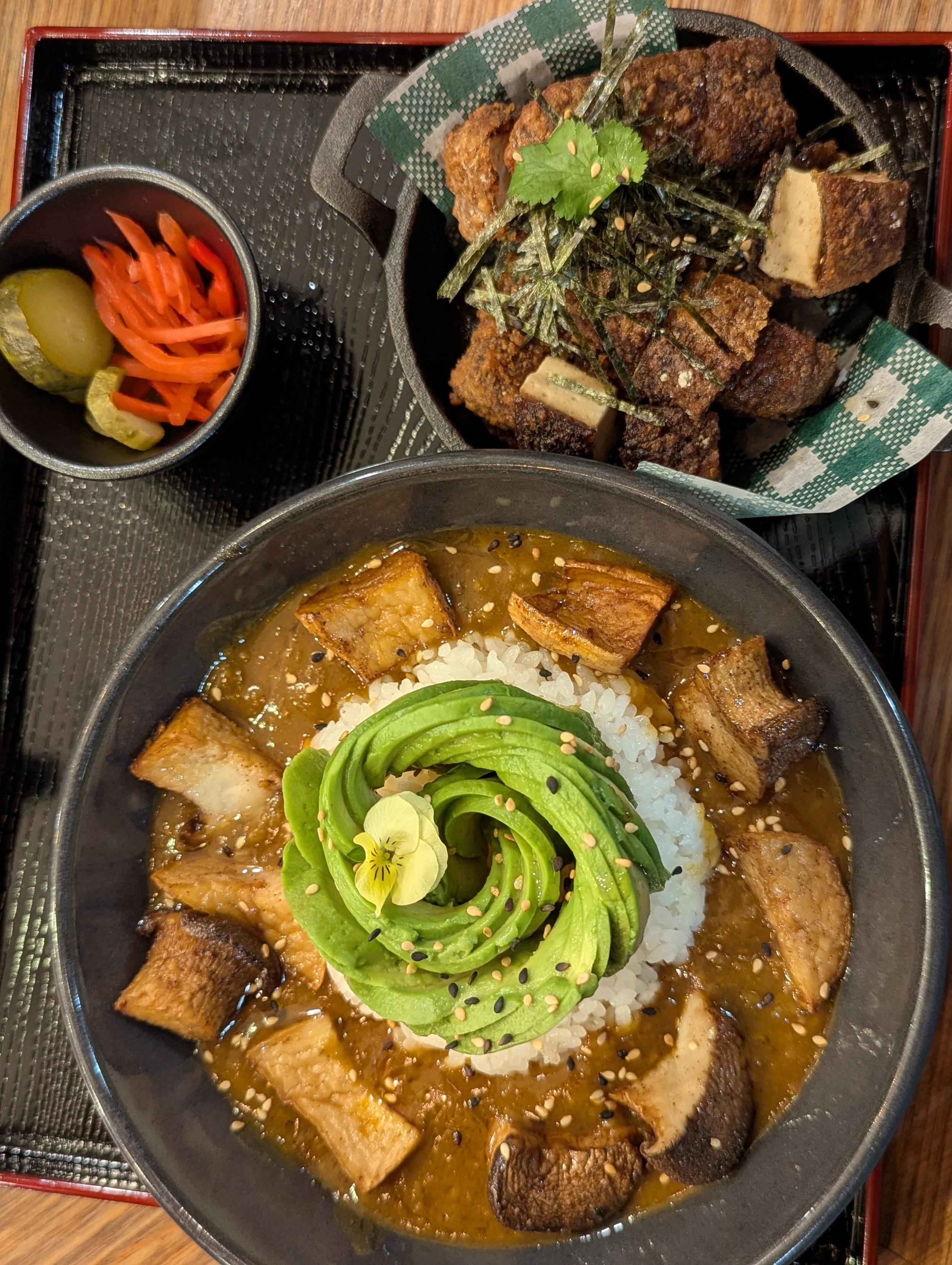 Japanese curry bowl with mushrooms topped with sliced avocado, and a side of crispy tofu