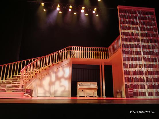 Scenery on stage for the play: book cases and staircase