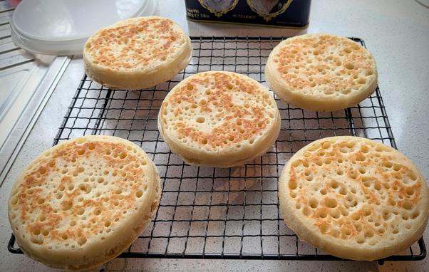 5 pretty handsome crumpets relaxing on a cooling rack. While the QEII tea caddy looks on in the background.